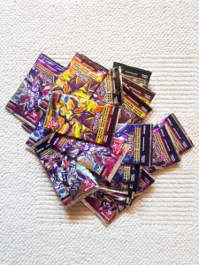 A heap of brand new Yu-Gi-Oh card booster packs laying on the carpet. Trading card games stack of packages
