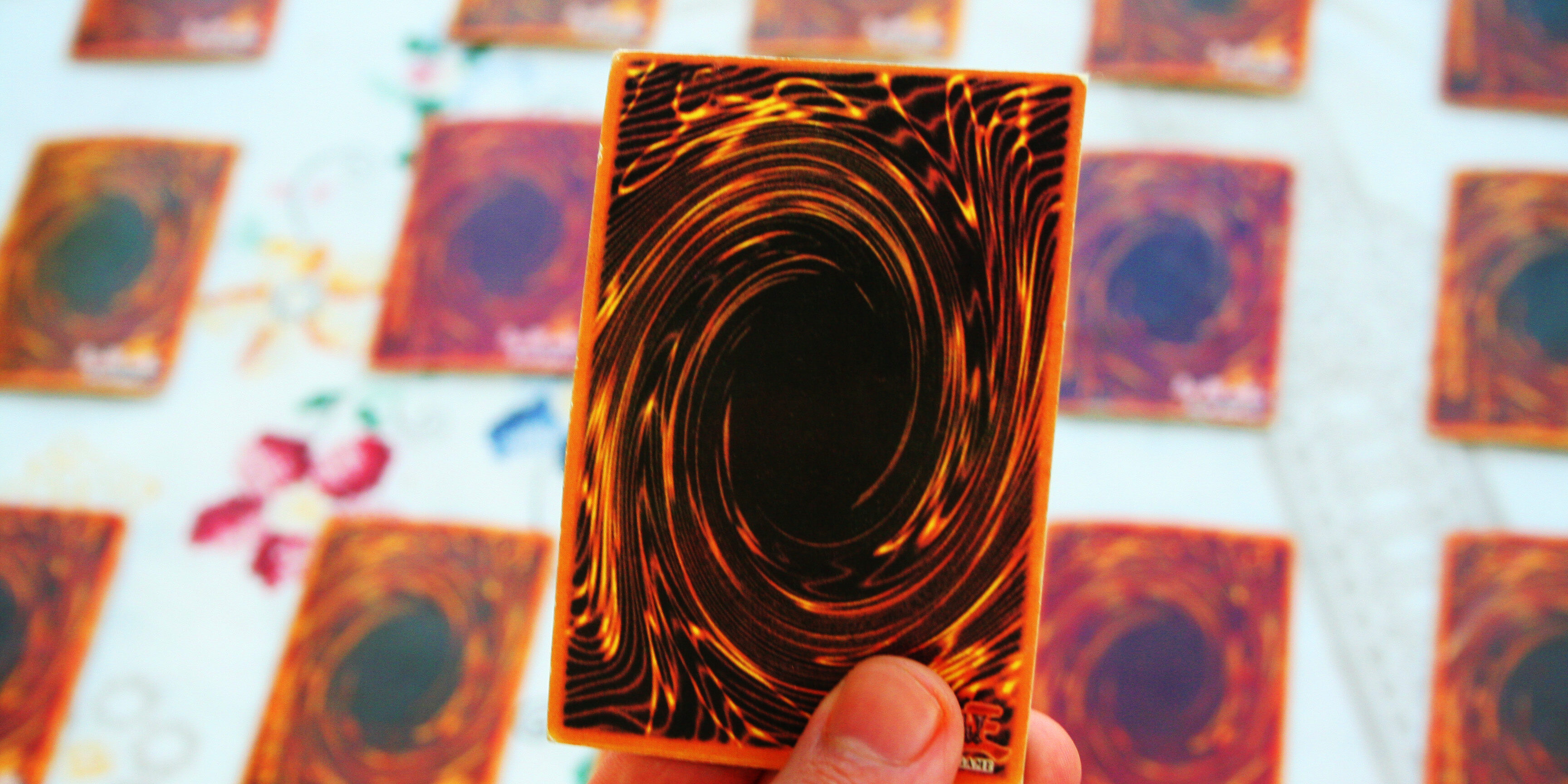 A Man holding a Yu-gi-oh game card from the back in his hand wit